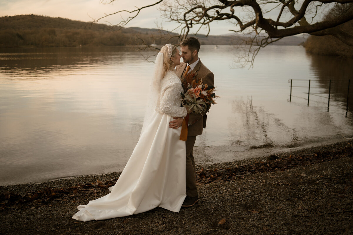 Cinematic wedding photography in Lake District, featuring a bride and groom kissing by the lake