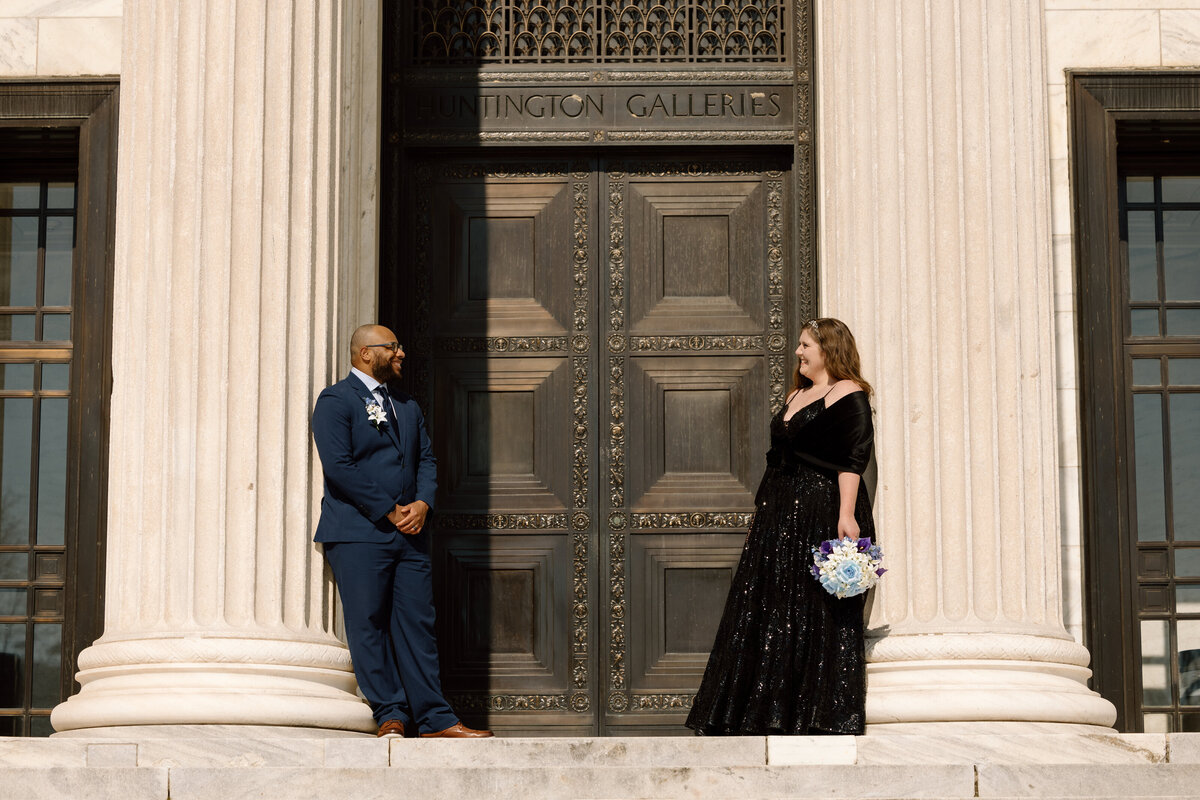 Bride and groom standing across from one another next to the pillars of the Cleveland Museum of Art.