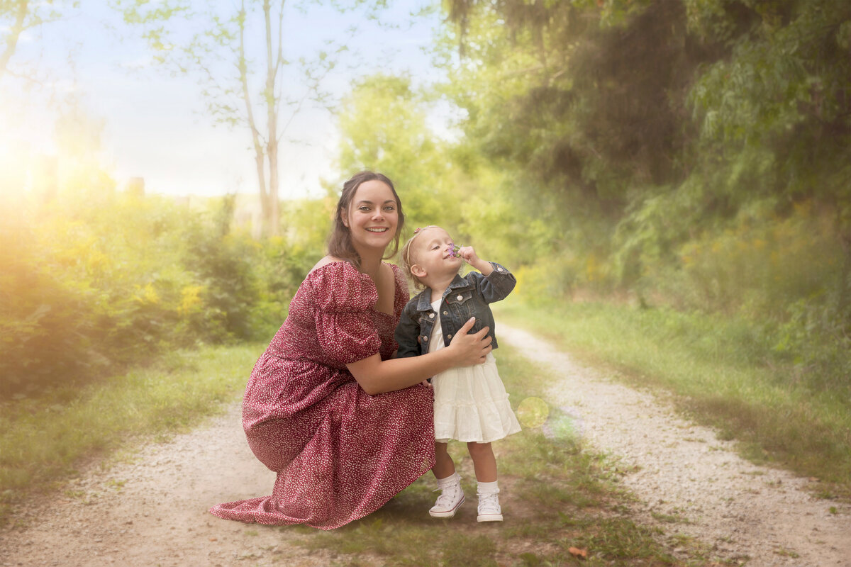 Whimsical outdoor portrait of a mother and daughter enjoying time together on a sunlit nature trail near Paris, Ontario. Photographed at Bronte Provincial Park in Oakville, Ontario.