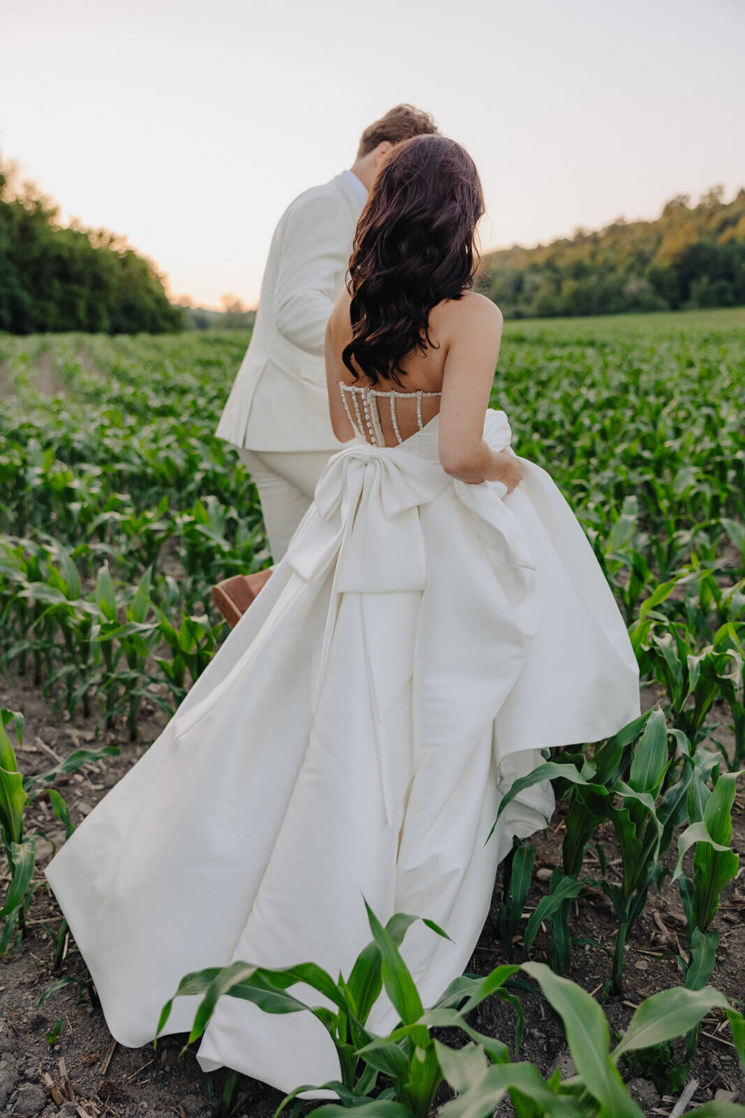 Bride and groom walking through corn fields at Finger Lakes wedding, NY at Wolf Oak Acres
