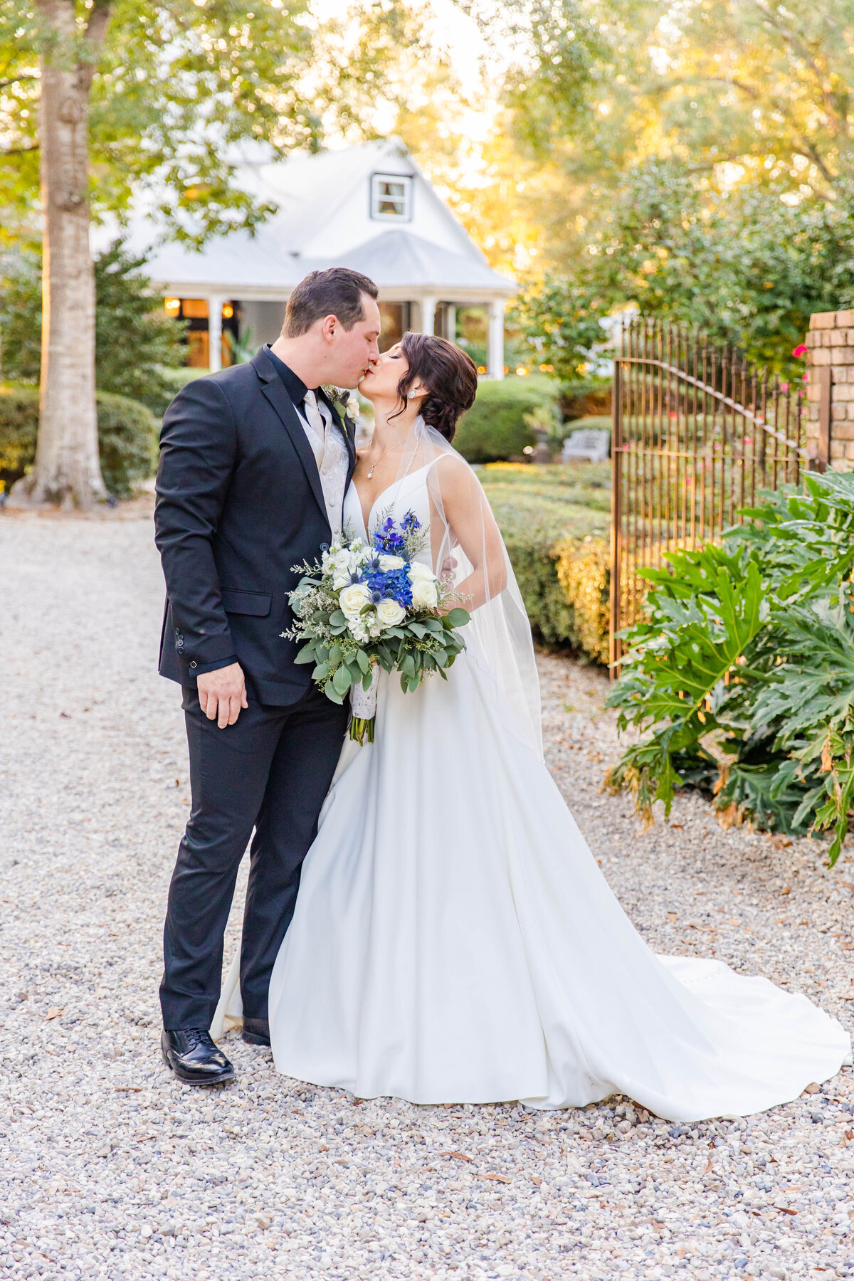 bride kissing groom in black suit in front of  the Henry Snith House in Mississippi