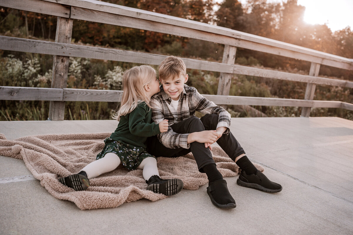 Sister and brother sitting on boardwalk