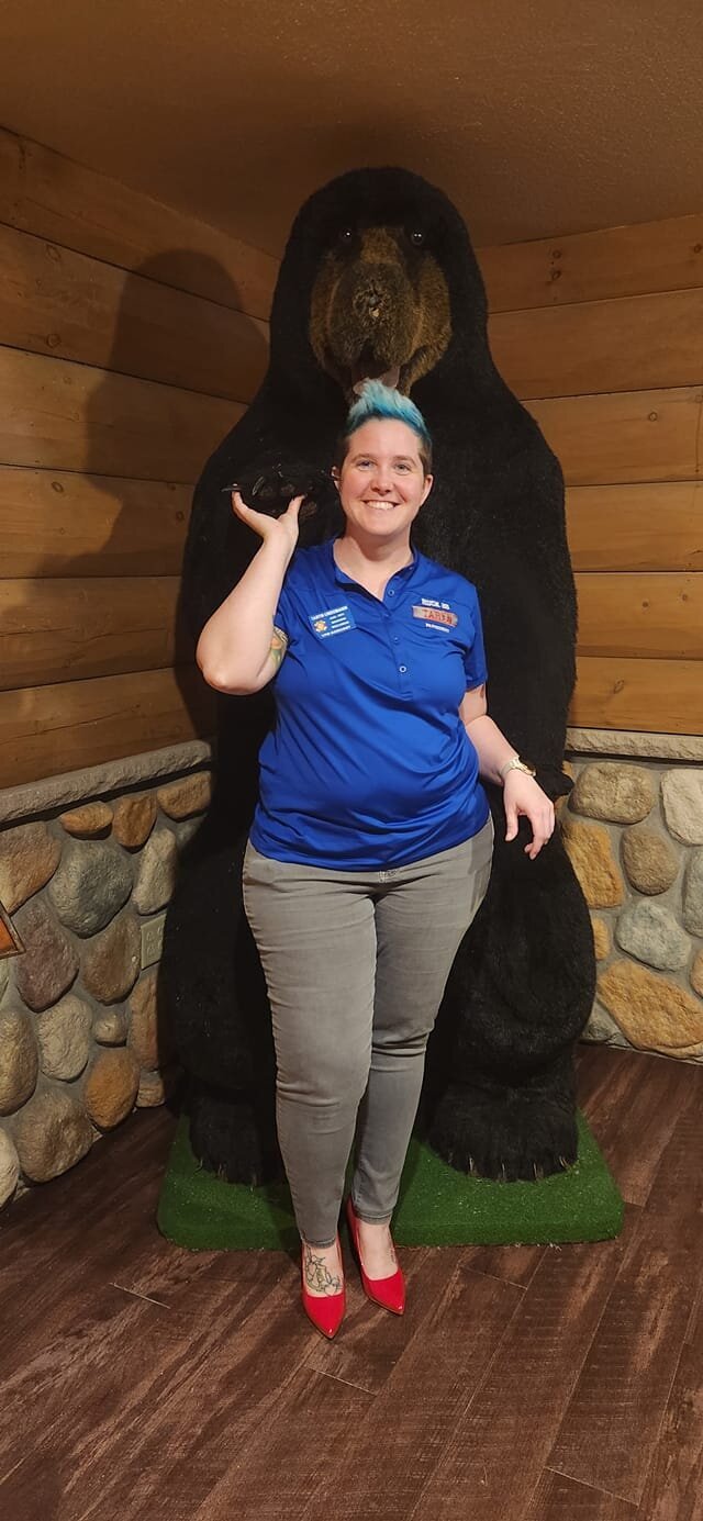 a woman poses with a taxidermied bear