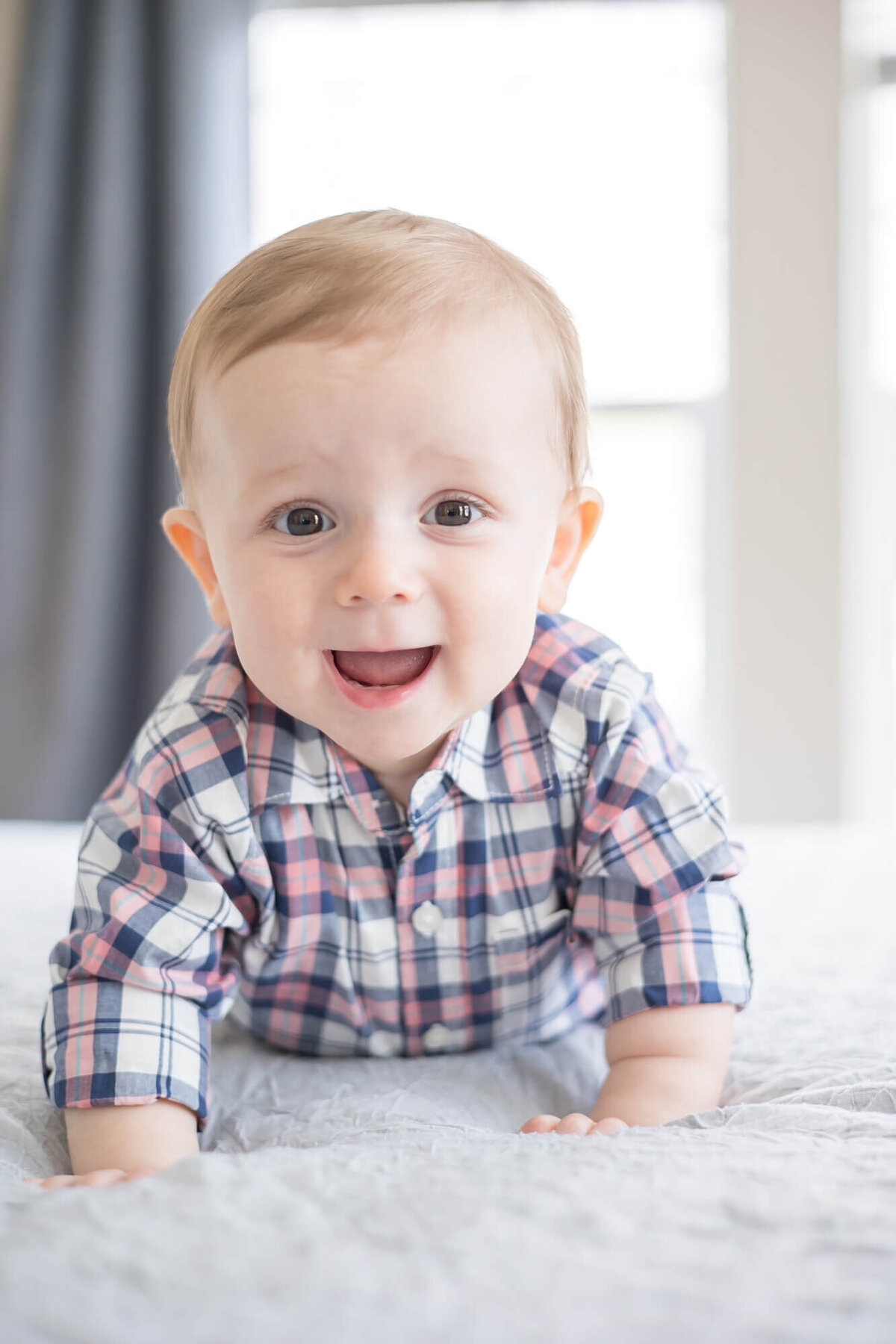 happy 9 month old baby boy on a bed