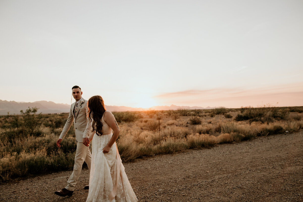 bride and groom walking  in the desert at sunset