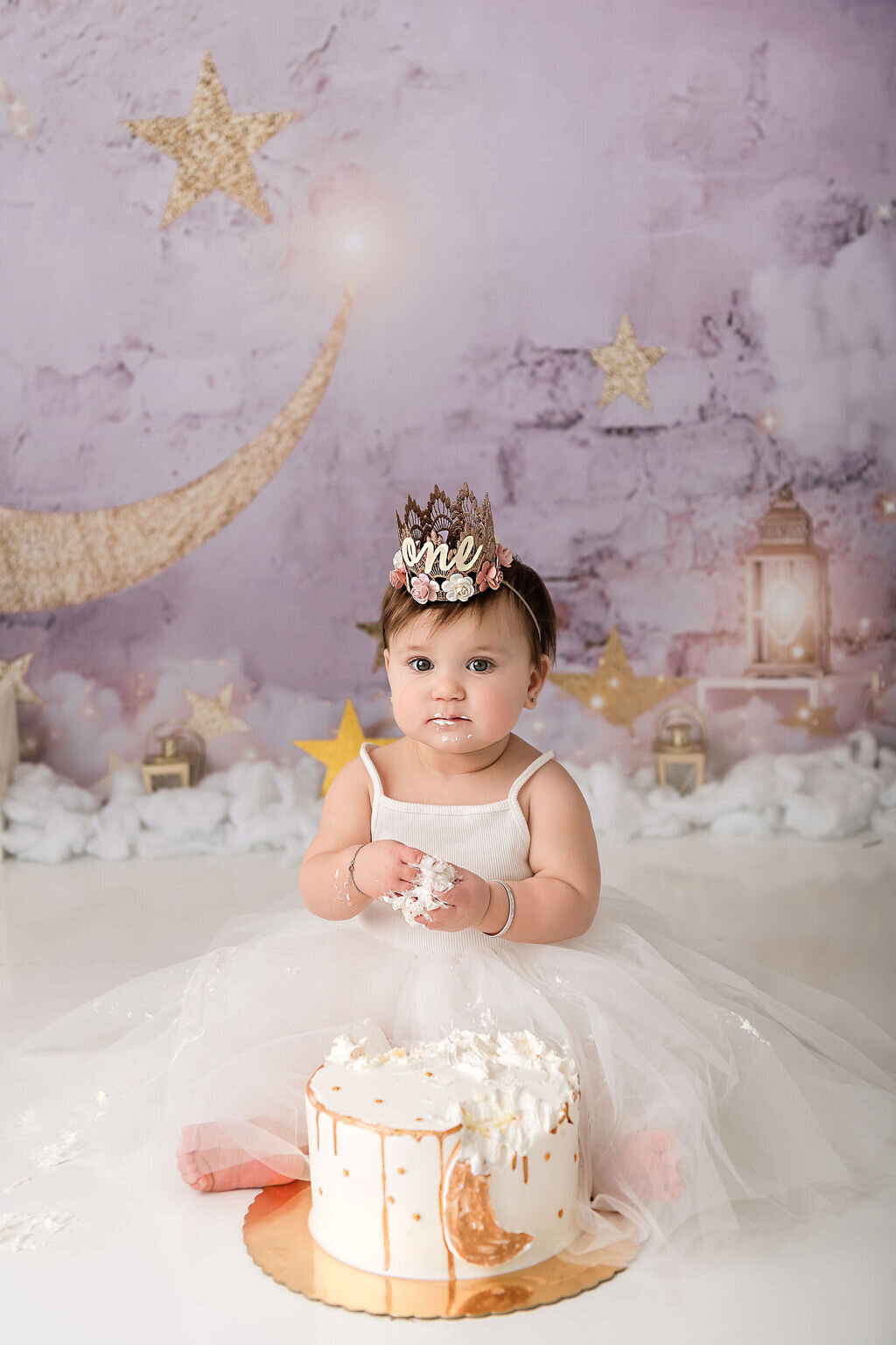 Portrait Photographers CT photograph precious moment as baby girl in cream tulle gown holds cake with golden crescent moon decoration