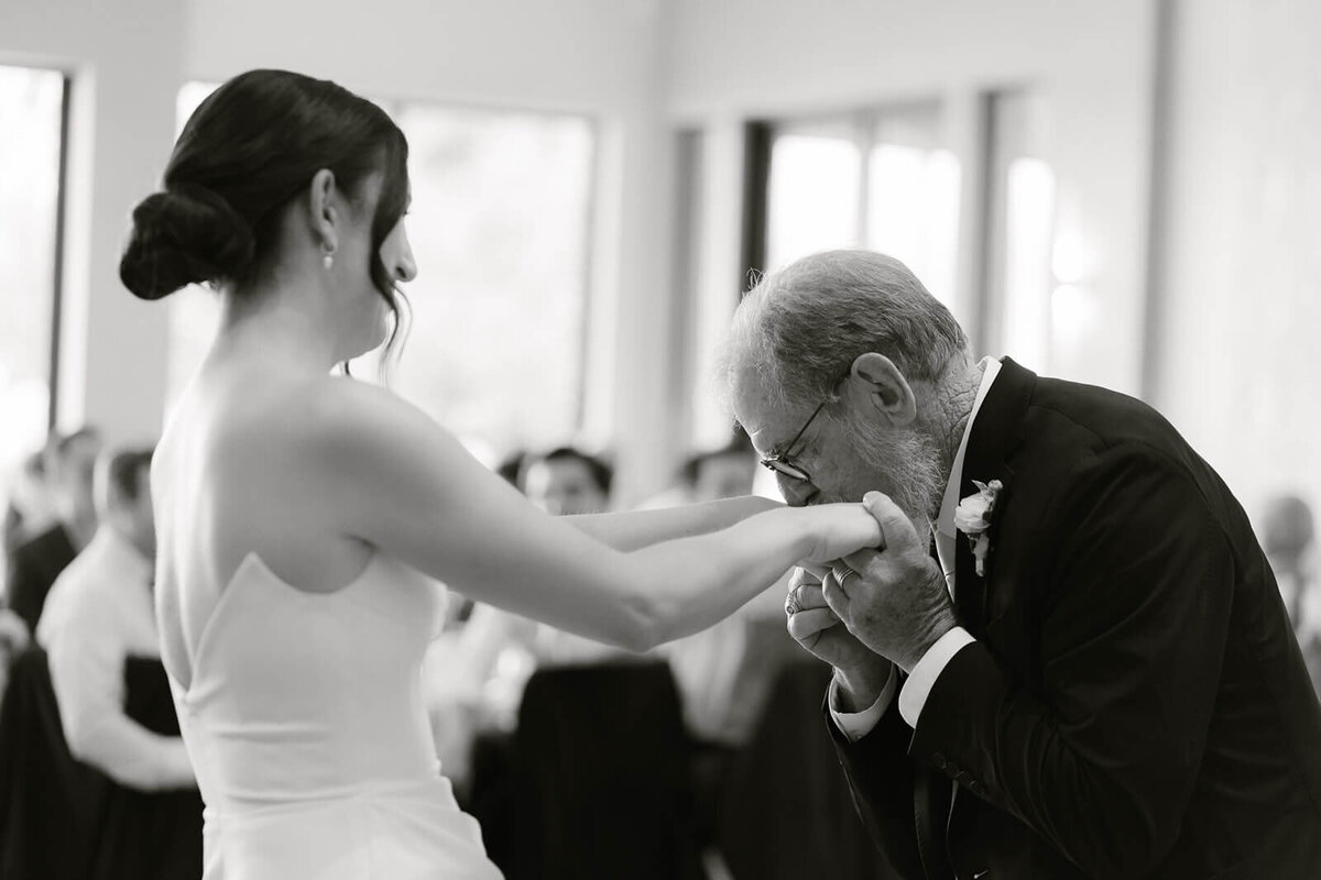 dad kisses his daughters hands after their dance