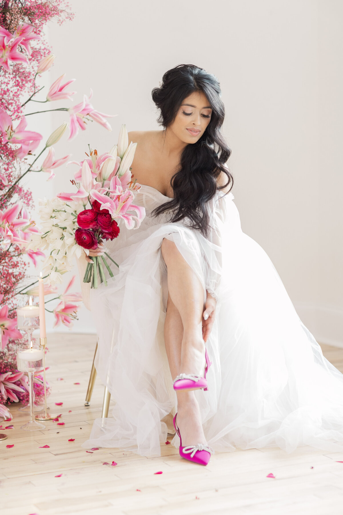 bride wearing bright pink shoes and surrounded by pink and white florals