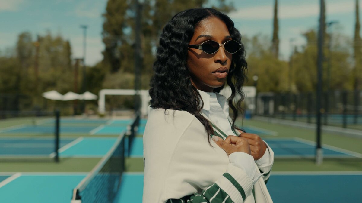 Shaniece Jones on a  tennis court wearing sun glasses.