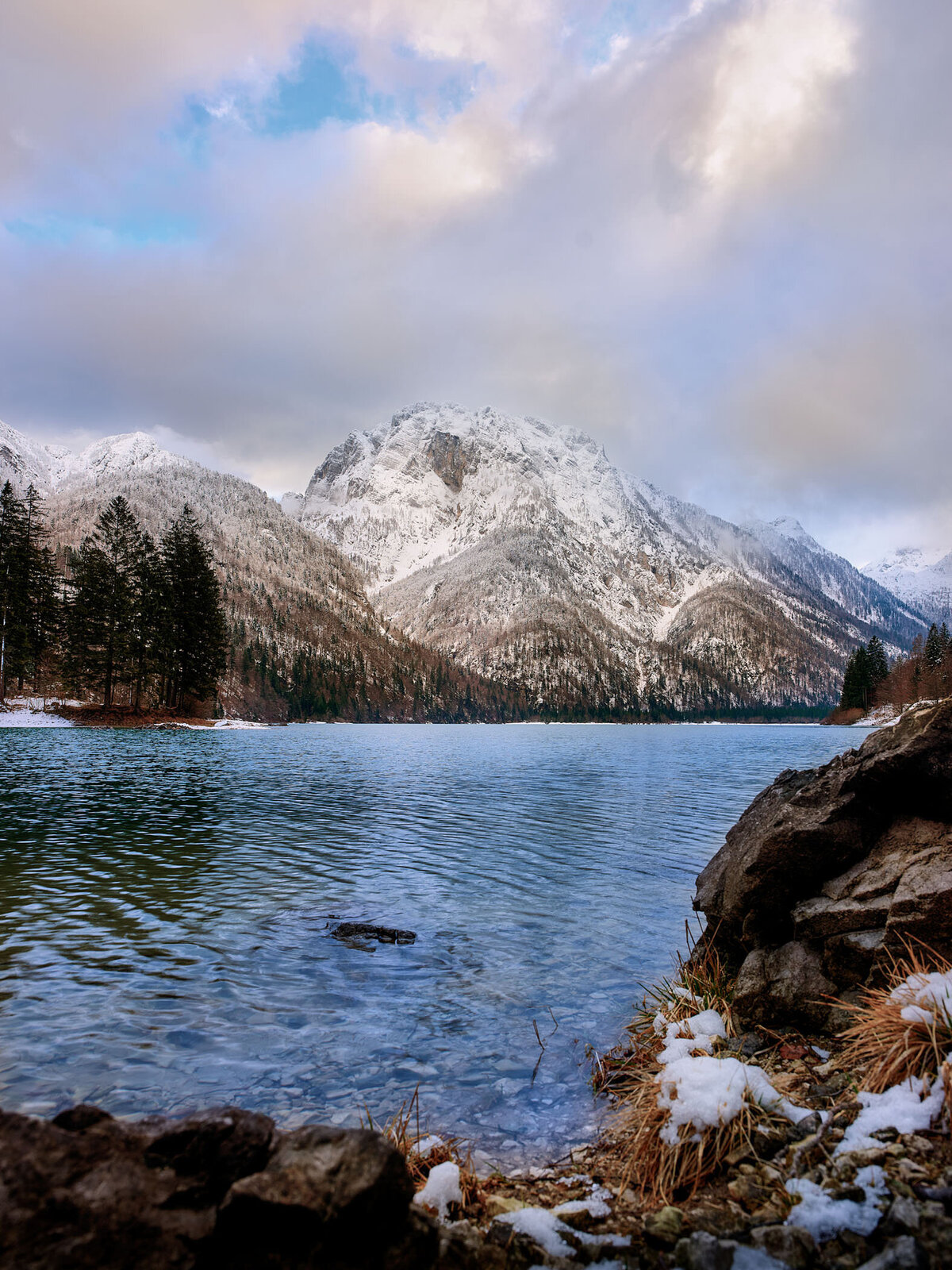Winterliche Landschaft am Lago di Predil mit verschneiten Bergen und ruhiger Wasseroberfläche – stimmungsvolle Fotografie von Spezialist für Alpenlandschaften Atelier Schulte.