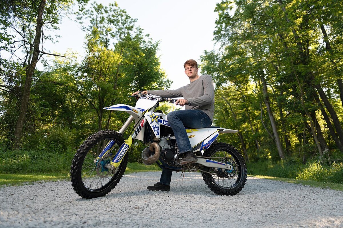 High school senior guy on dirt bike on gravel path lined with trees