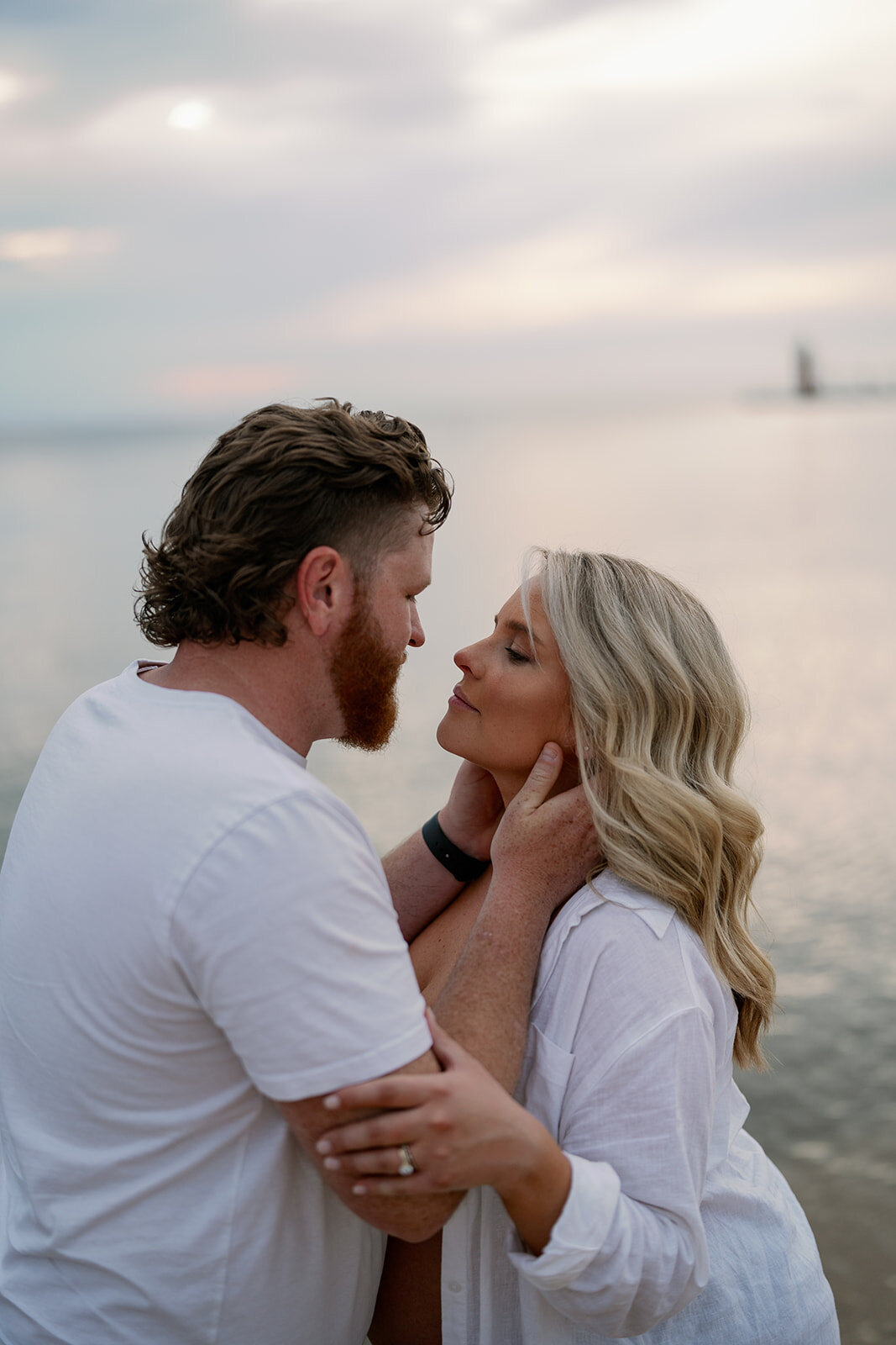 Pregnant couple kissing near the water during sunset maternity session at South Haven North Beach.