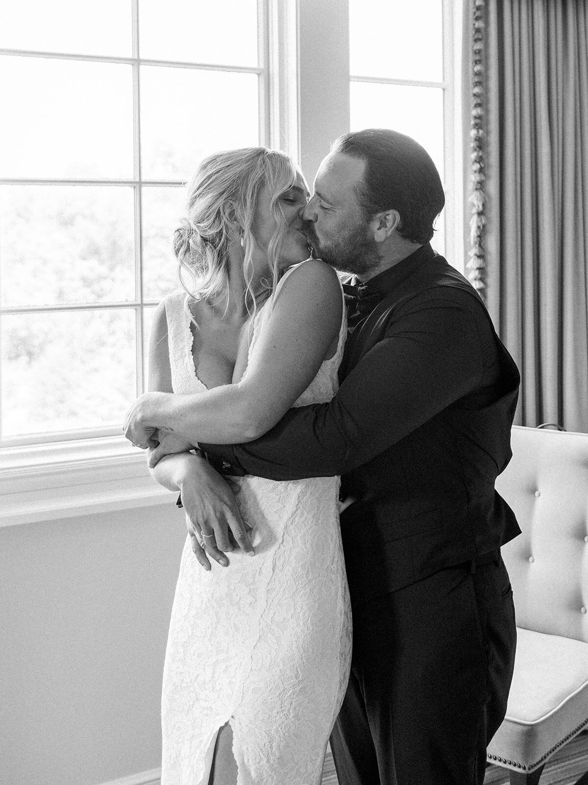 Groom hugs his bride from behind as she turns back to kiss him