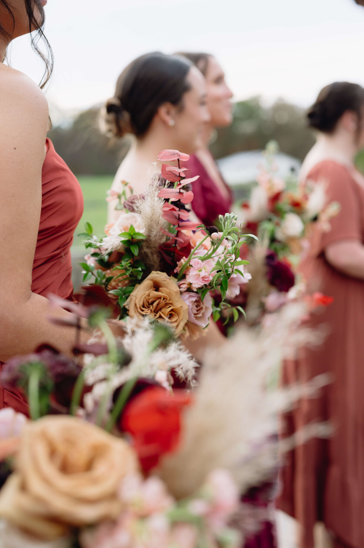 detail shot of boho warm tone wedding bouquets held by bridesmaids during the ceremony captured by Charlottesville wedding photographer