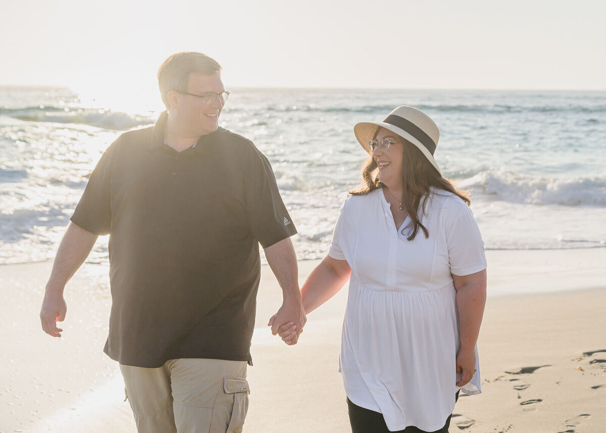 Jospeh and Melissa holding hands while walking on the beach in La Jolla, California