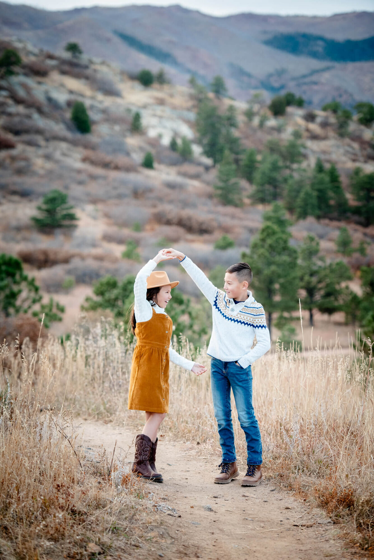 An image captured by a Colorado Springs family photographer of a young boy spinning his younger sister by the hand on a trail