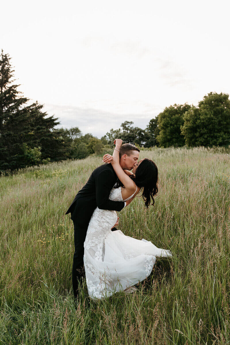Bride and groom kissing in a field by luxury wedding planner chicago