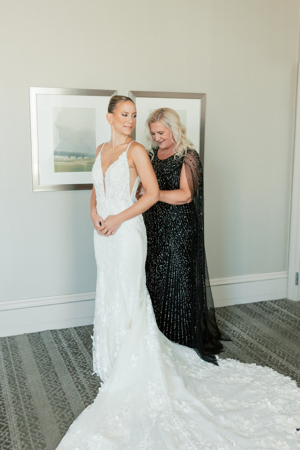 Bride getting buttoned into her lace gown by her mother, captured by a Philadelphia wedding photographer.