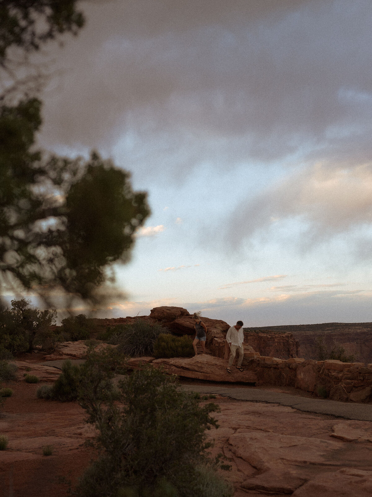 couple walking along the cliff's edge during sunset in Moab, Utah