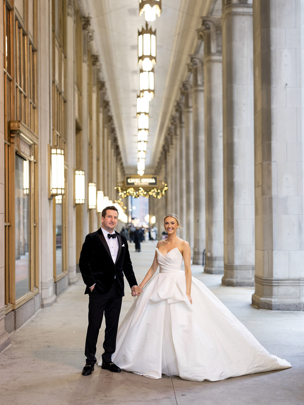 A bride and groom hold hands posing for a photo at the Palmer House in Chicago.