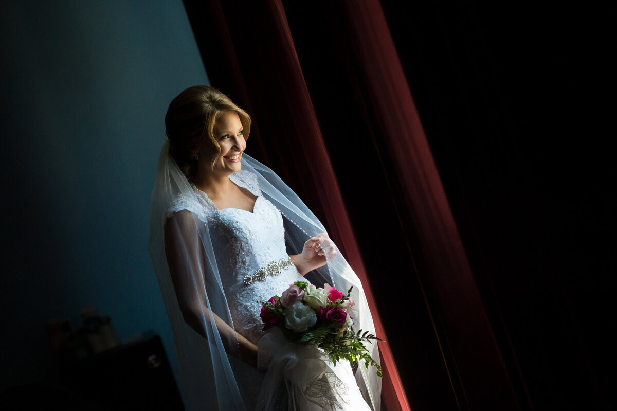 Bride looking out window at wedding ceremony.