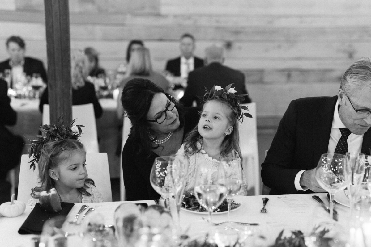 mother of the bride and flower girl sitting together at wedding dinner