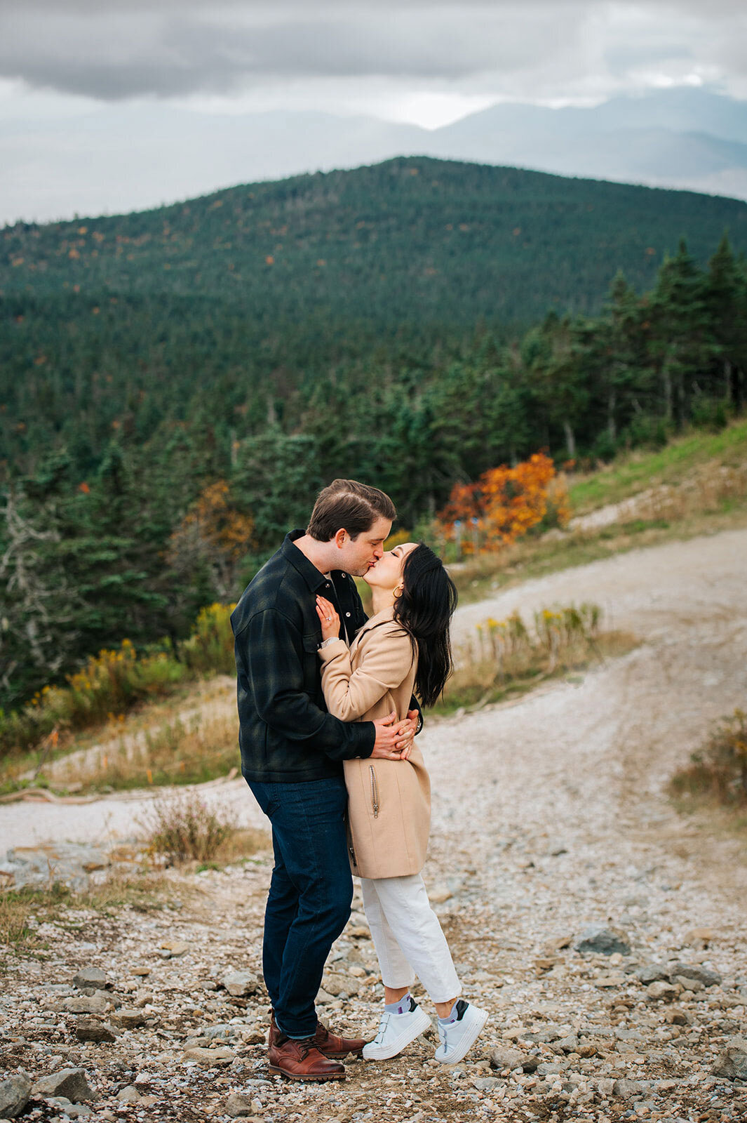 engaged couple kissing on mountain top killington resort fall in vermont