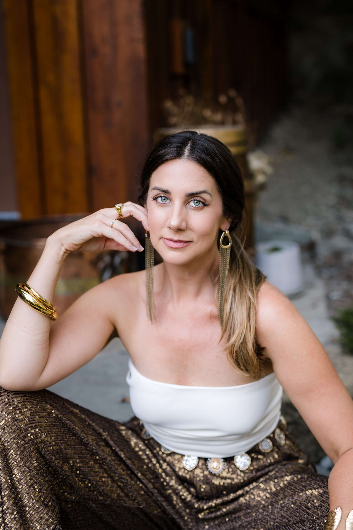confident woman wearing gold sequined outfit looking at camera for golden hour headshot
