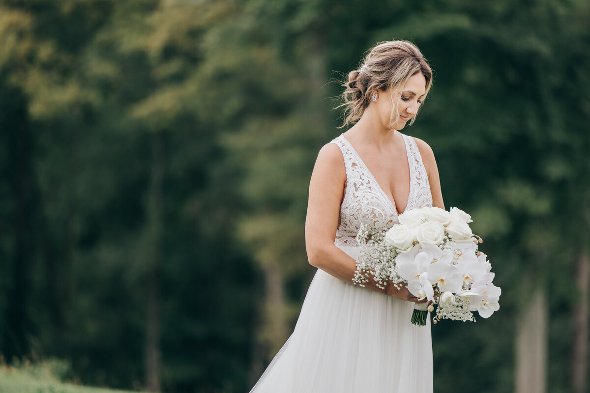 Bride posing for traditional photos with an elegant white wedding bouquet