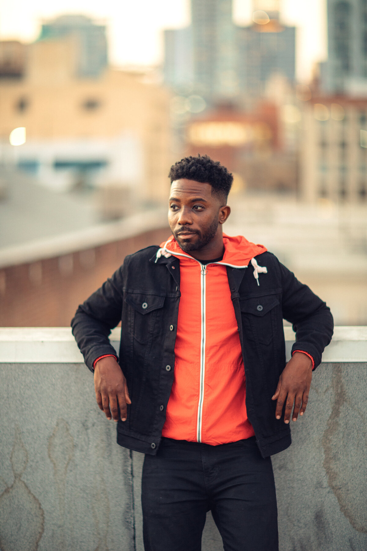 Portrait Photo Of Young Black Man In Outer Black Jacket And Inner Orange Hoodie Los Angeles