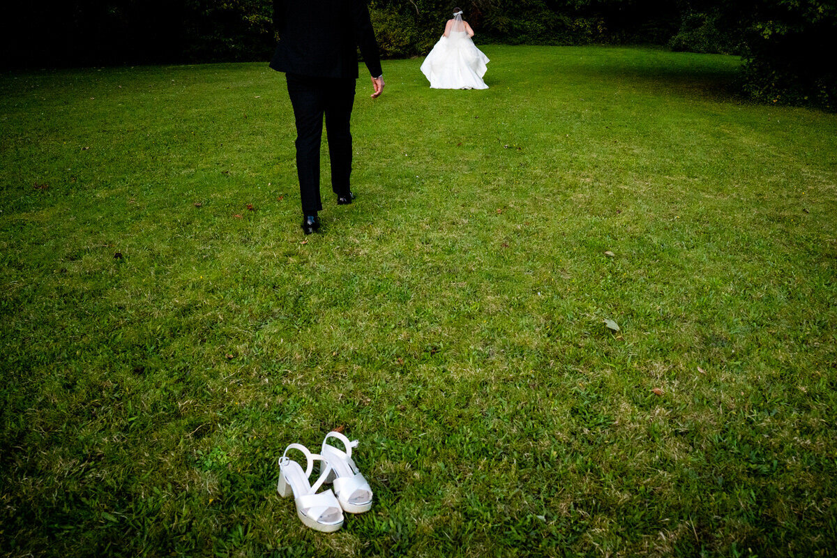 Wedding couple running away into the distance with the brides wedding shoes in the foreground