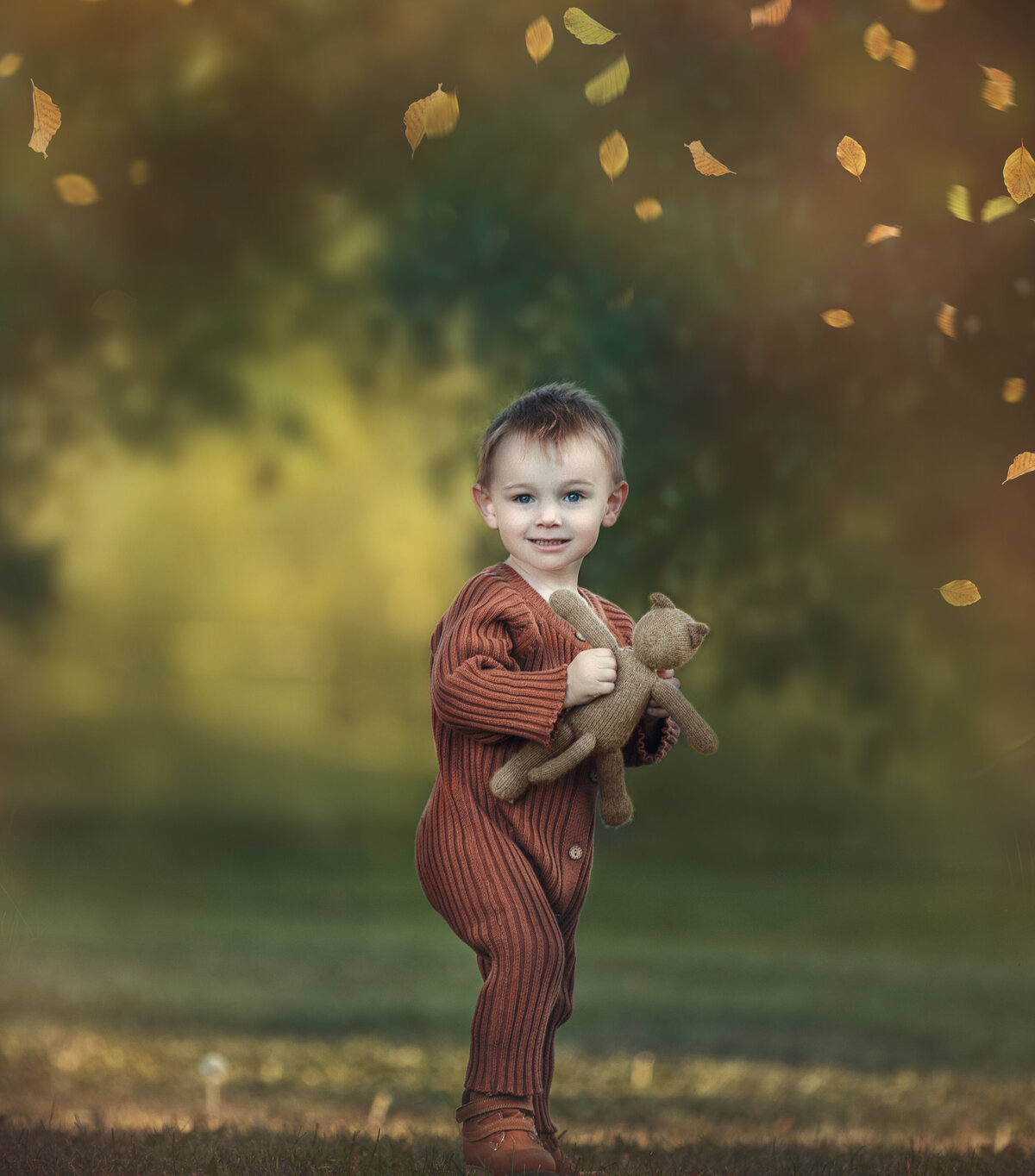 toddler boy playing with teddy bear during his fall outdoor photography session in Ottawa Ontario