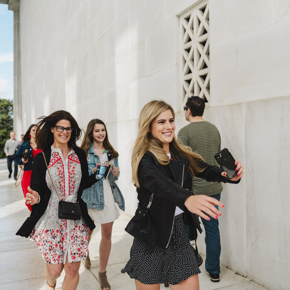 Family runs excitedly to hug a newly engaged couple at the Lincoln Memorial.