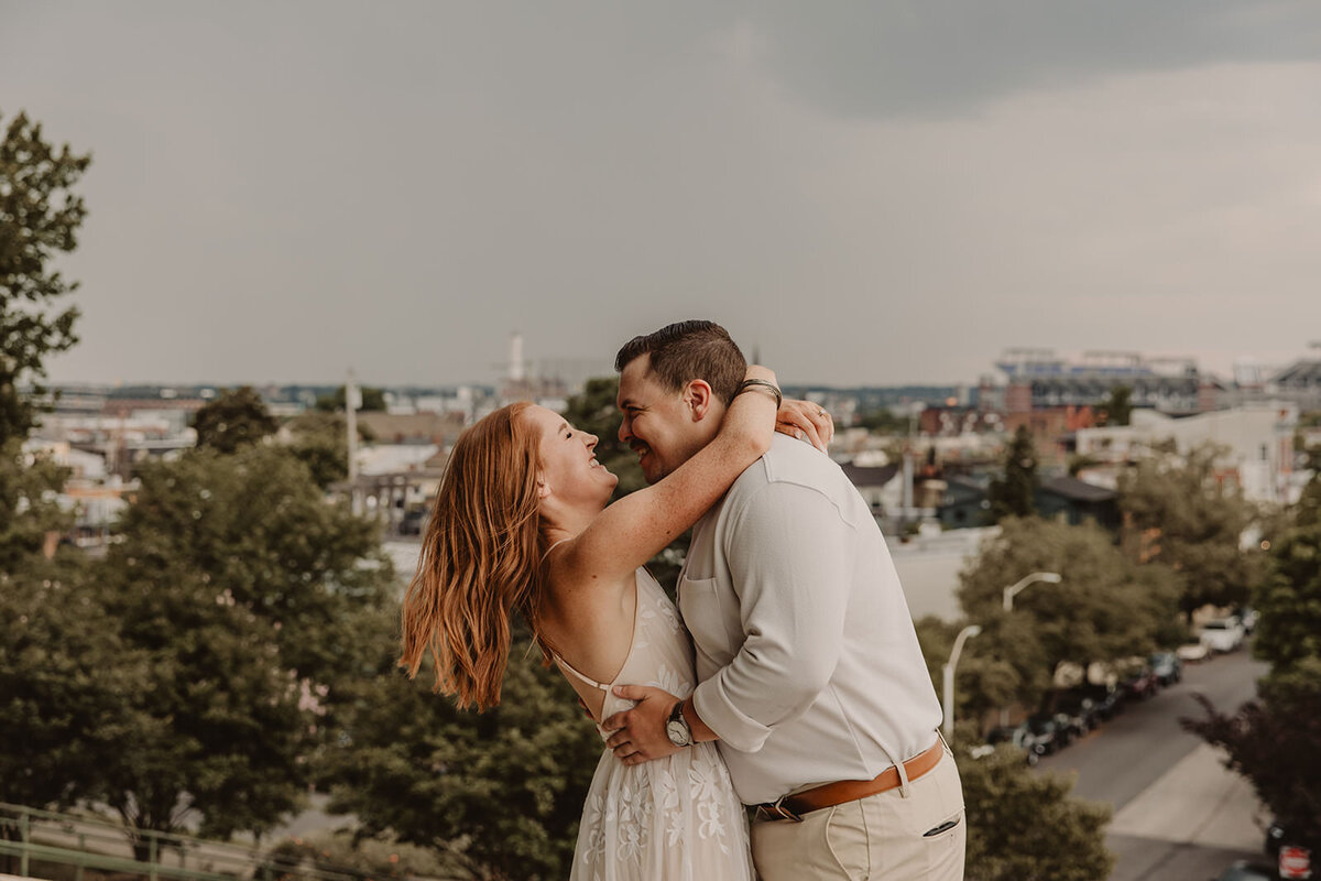 A couple with their arms around each other leaning in together 