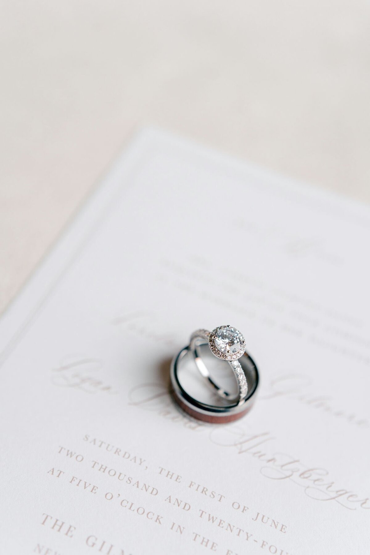 Close-up shot of wedding rings on a beautifully designed wedding invitation, highlighting the intricate details.