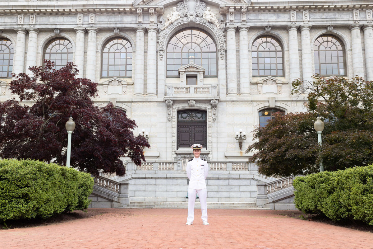 Naval Academy graduate senior portrait in white uniform at Mahan Hall.