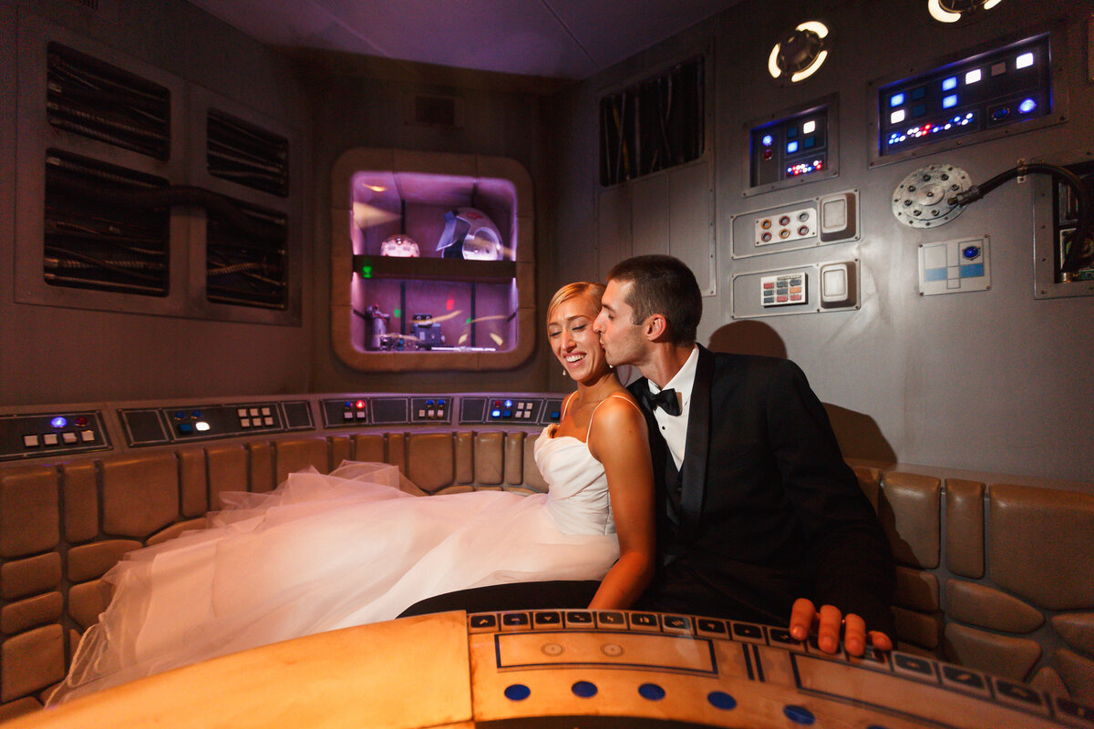 groom kissing bride on the cheek in oceaneers lounge start wars area on Disney dream