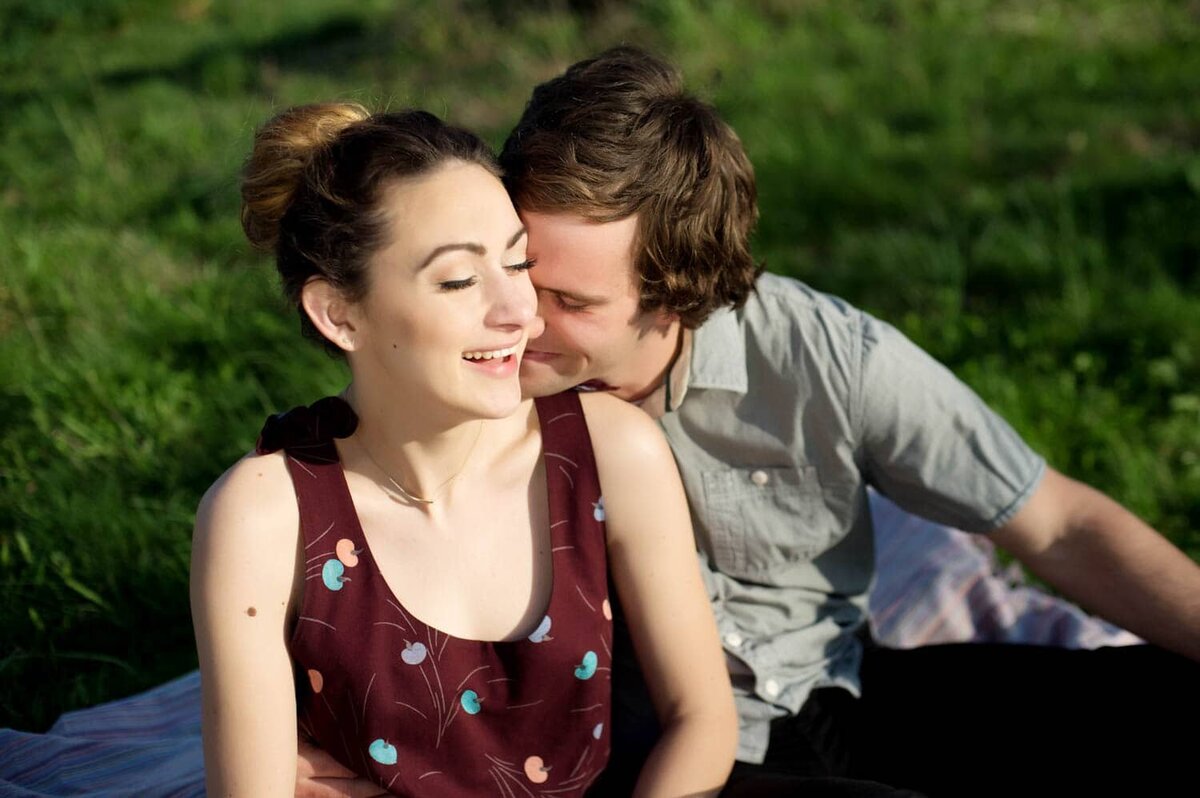 a man nuzzles into the neck of a woman while sitting outside