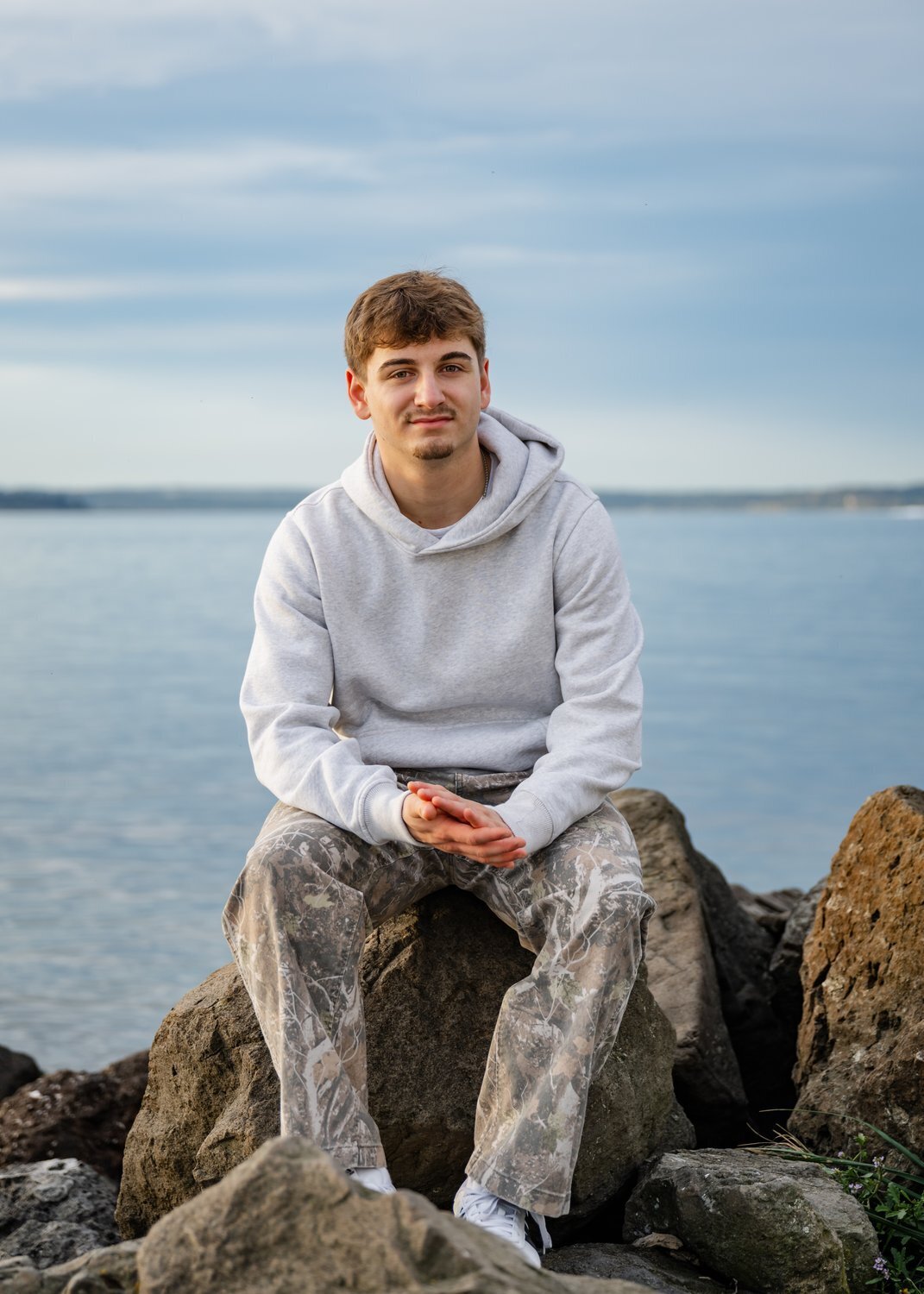 issaquah high school senior sitting on rock by puget sound