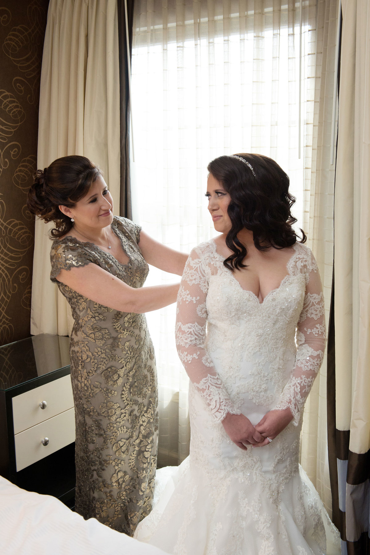 Bride and mother putting on bride's dress at The Inn at Fox Hollow