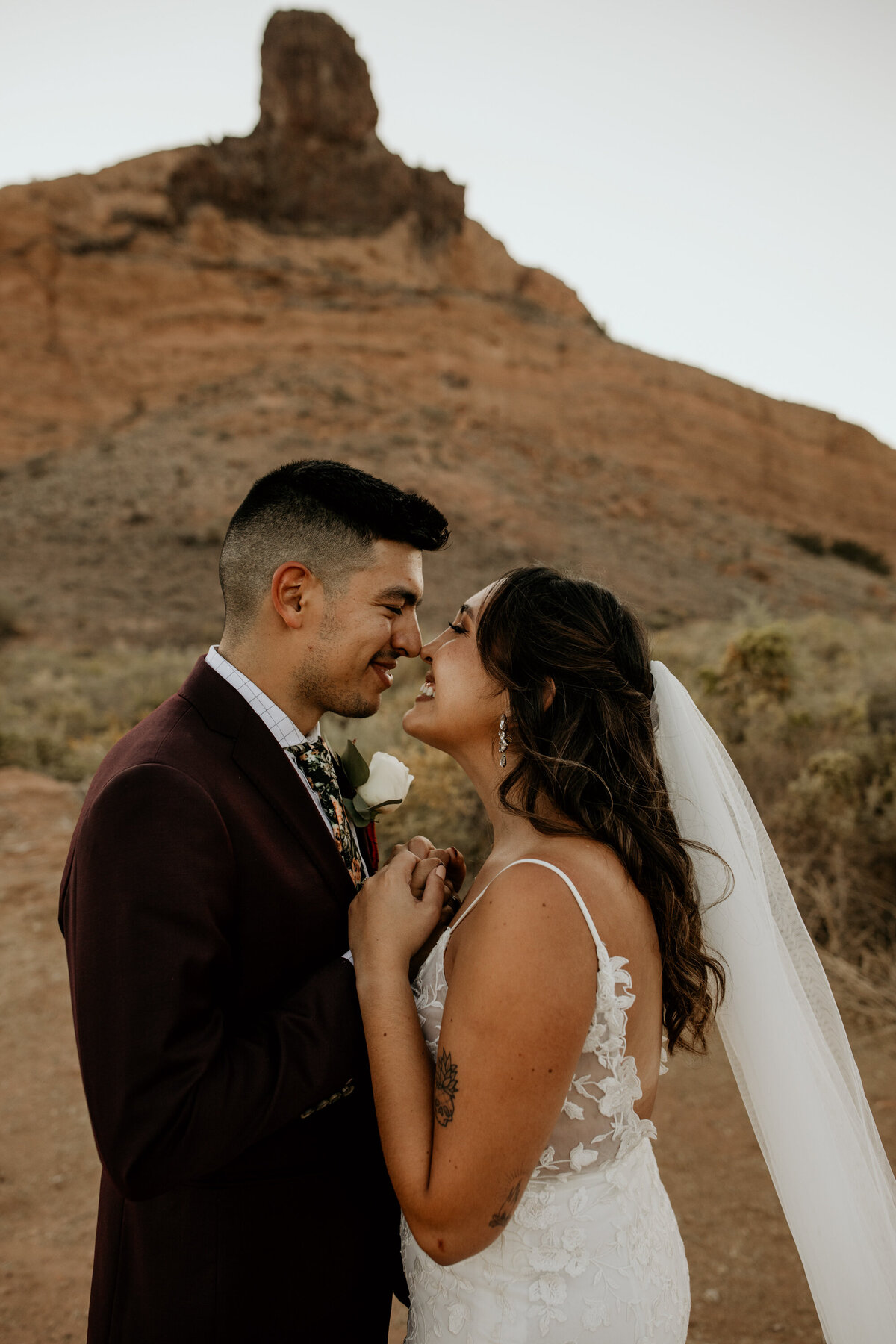 bride and groom with their noses together in the desert