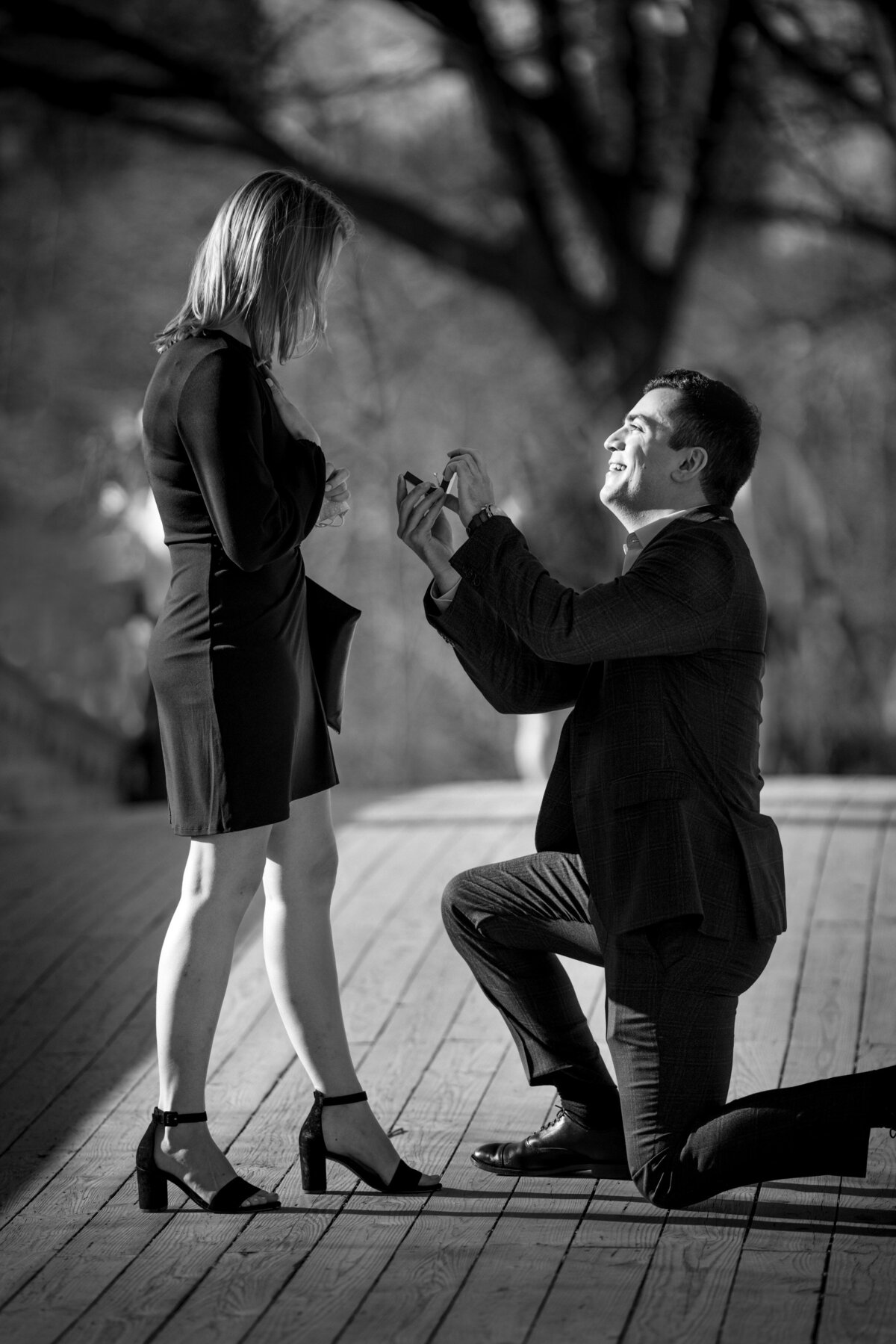 A man kneeling down proposing to a woman.