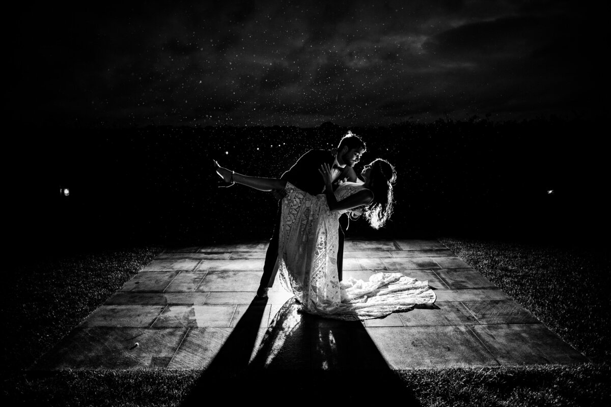 Black and  white backlit photograph of a bride and groom.