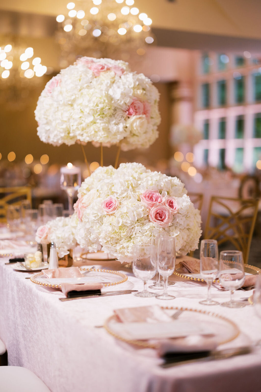 table setting with pink and white florals, elegant glasses, and glass plates with gold accents