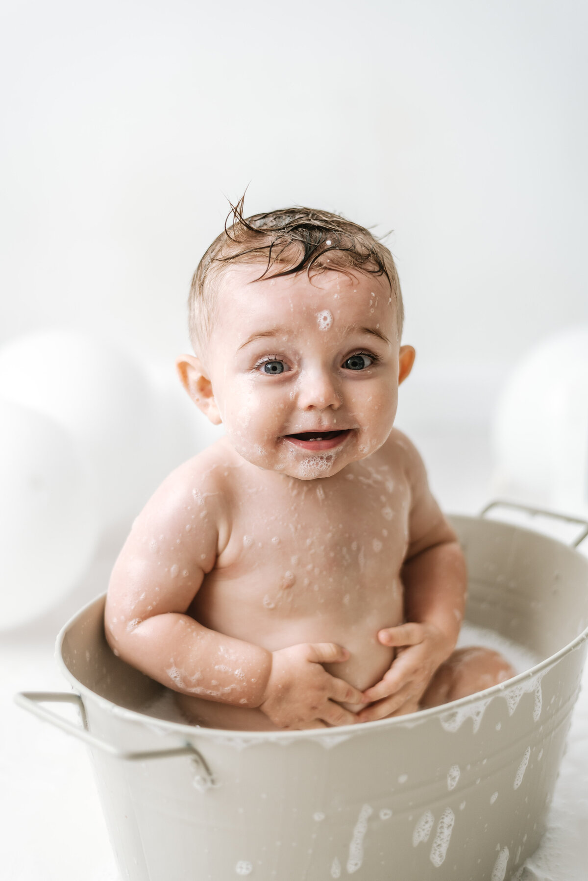 Baby boy in a bubble bath at cake smash photoshoot in Billingshurst