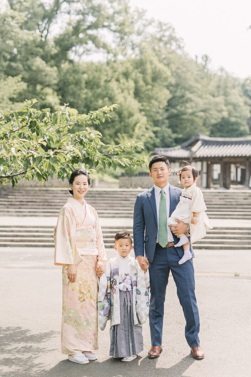 5歳男の子の七五三前撮り。家族で桜の木の下で並んでいる。和装が素敵な家族写真。