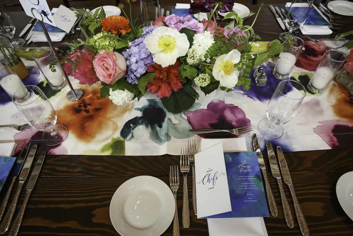 wood table with colorful table runner and colorful centerpiece with poppies, roses, maidenhair ferns