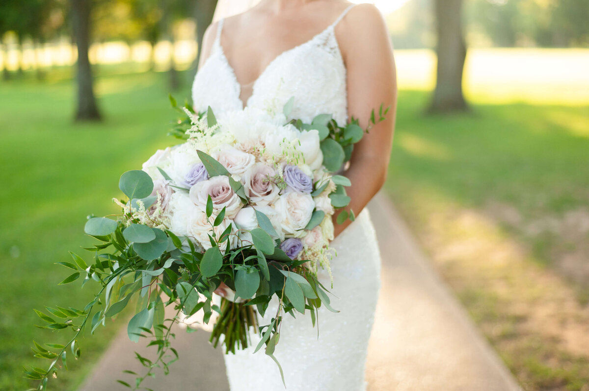 bride holding bouquet of roses at greenery at wedding at Stones River Country Club