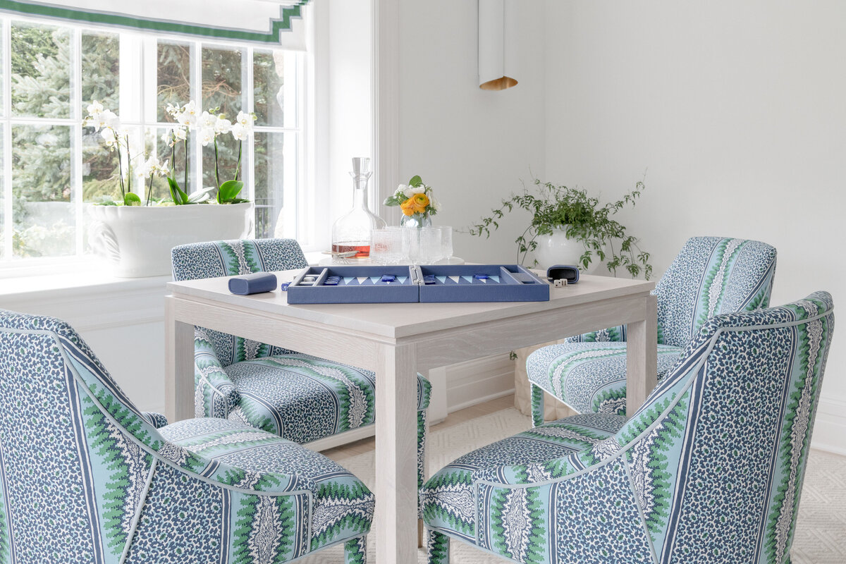Game Room table design with heavily patterned blue and green chairs.