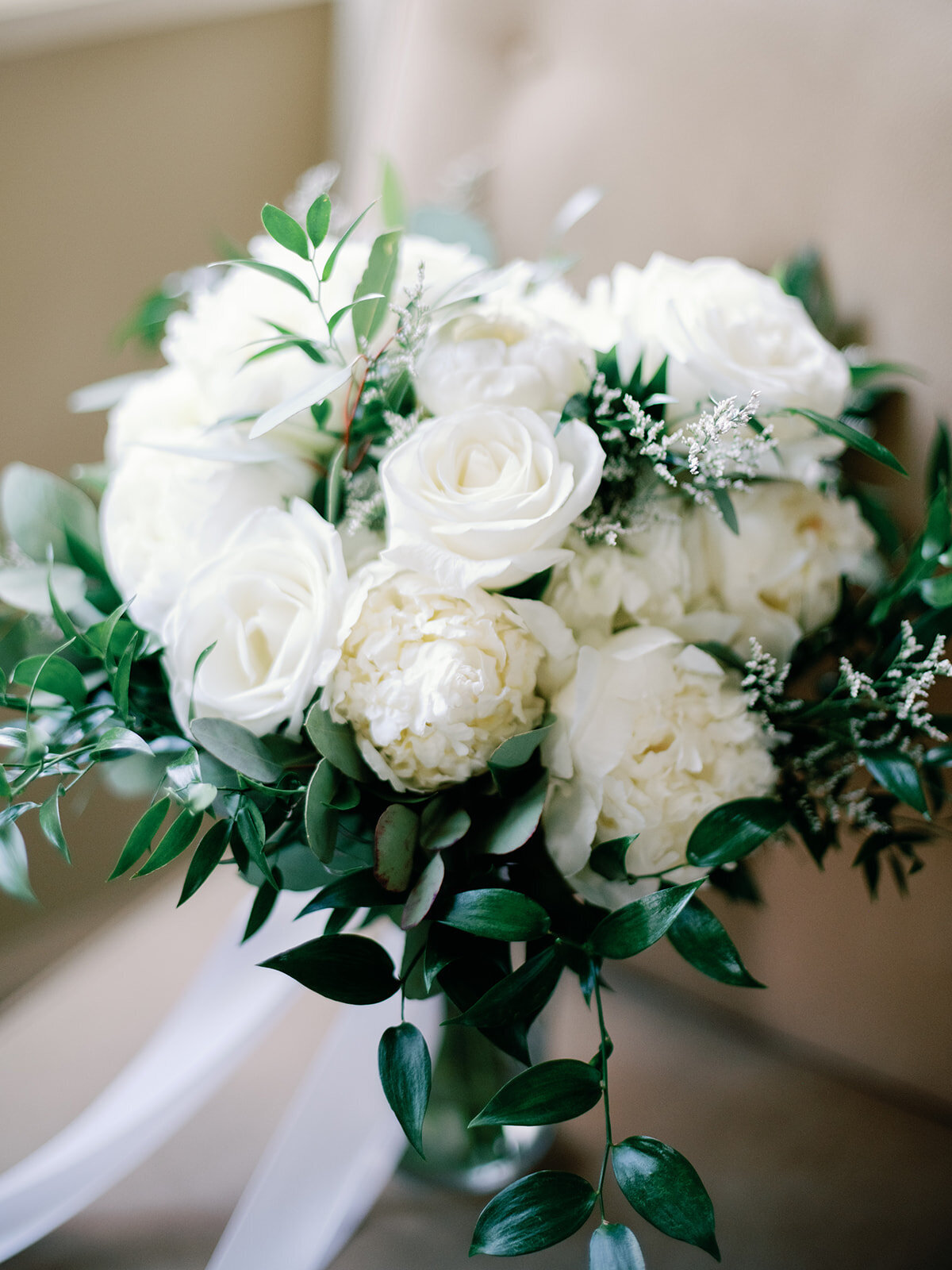A white bouquet of flowers for a bride sitting on a chair.